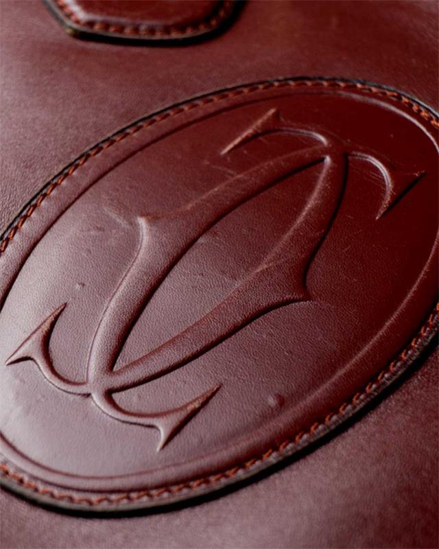 Dettaglio della lavorazione e logo su borsa Cartier in pelle.
